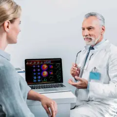 Arzt erklärt Patientin die Ergebnisse einer Mibi-Szintigraphie und bespricht mögliche Risiken.