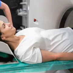 Frau liegt auf Liege für PET-CT-Untersuchung. Rote Laserlinien markieren Position.