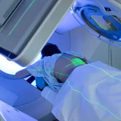 Patient unterzieht sich einer Bestrahlung des Kopfes. Grüne Laserlinien markieren die Behandlungszone auf dem Körper.