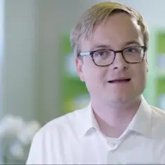 Ein Mann mit Brille in einem weißen Hemd spricht. Er erklärt, dass es erleada eine Chemotherapie ist.