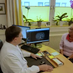 Arzt bespricht CT-Scan mit Patientin. Die Lebenserwartung bei Lungenkrebs Stadium 2 ist ein wichtiges Thema.