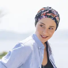 Frauen mit einem gebundenen Kopftuch, das sie während der Chemo tragen, lächeln zuversichtlich in die Kamera.