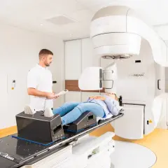 Frau liegt auf Behandlungsliege für Prostata-Bestrahlung. Arzt überwacht den Vorgang. Alkohol ist hier fehl am Platz.