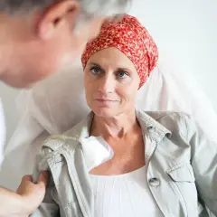 Ärztin spricht mit Patientin, die eine Kopfbedeckung trägt, während sie eine hyperthermie therapie erhält.