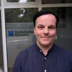 Mann vor Grafschafter Diakonie-Gebäude. Hier gibt es sozialberatung bei Krankheit.