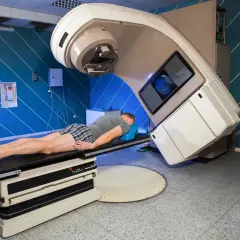 Mann liegt auf Behandlungsliege unter einem Bestrahlungsgerät. Dies ist ein wichtiger Schritt bei der Behandlung von Lungenkrebs.