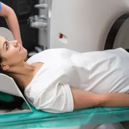 Frau liegt auf Liege für PET-CT-Untersuchung. Rote Laserlinien markieren Position.