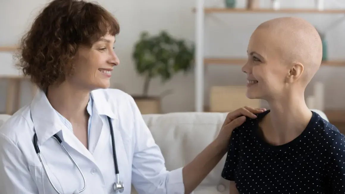 Ärztin tröstet Patientin, die ihre Haare wegen Chemotherapie verloren hat. Hoffnungsvolles Gespräch über die Chemotherapie Dauer.