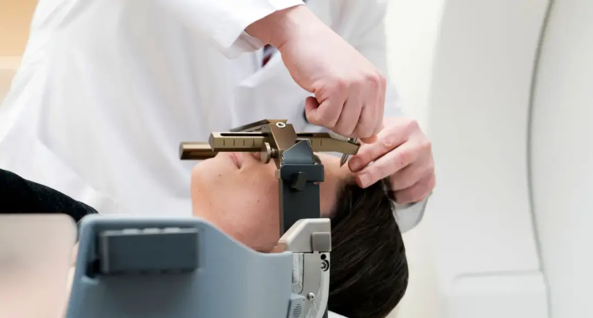 Arzt justiert stereotaktische Vorrichtung am Kopf einer Patientin. Informationen zu stereotaktische bestrahlung kosten sind hier nicht ersichtlich.