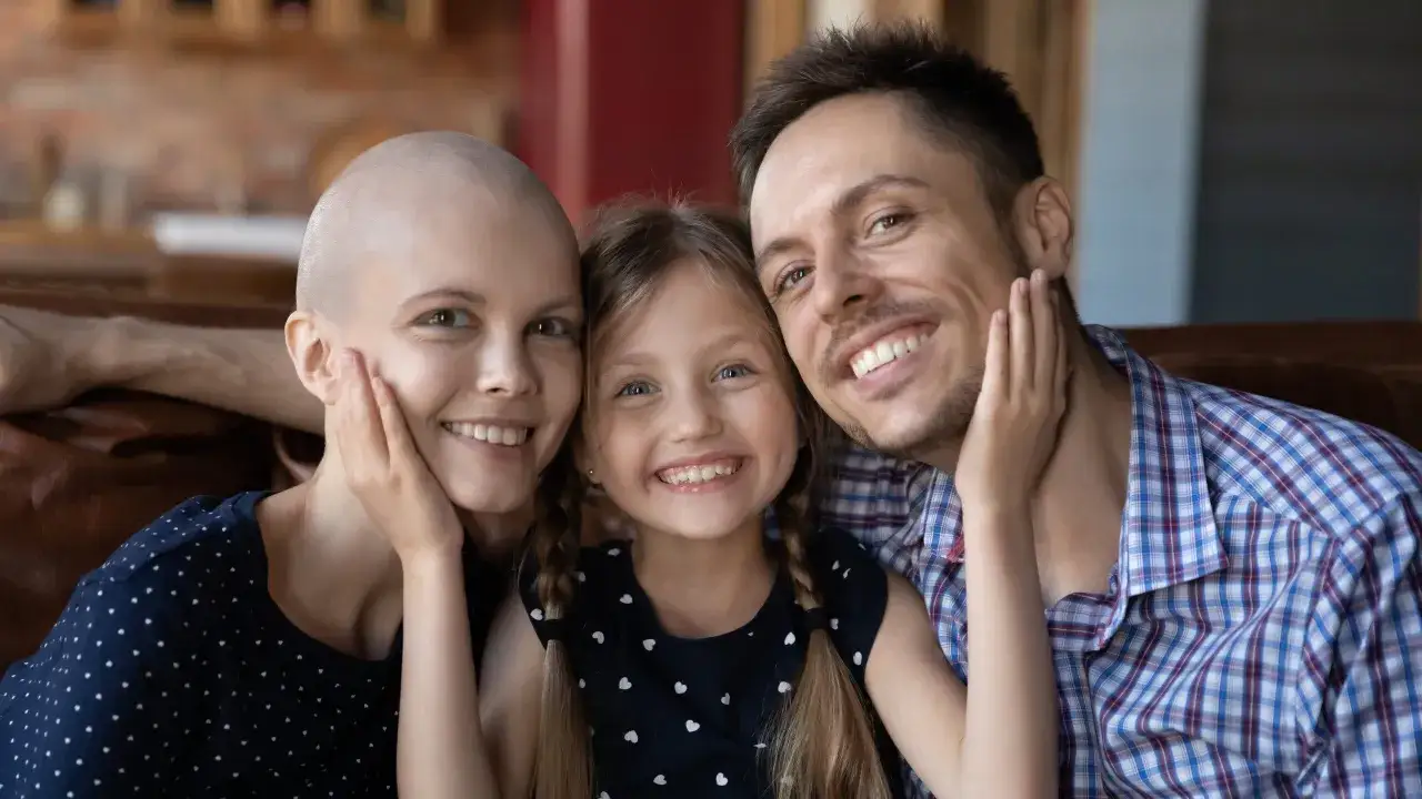 Familie zeigt Stärke und Liebe. Die Mutter, die eine Chemotherapie macht, lächelt mit ihrem Mann und ihrer Tochter.