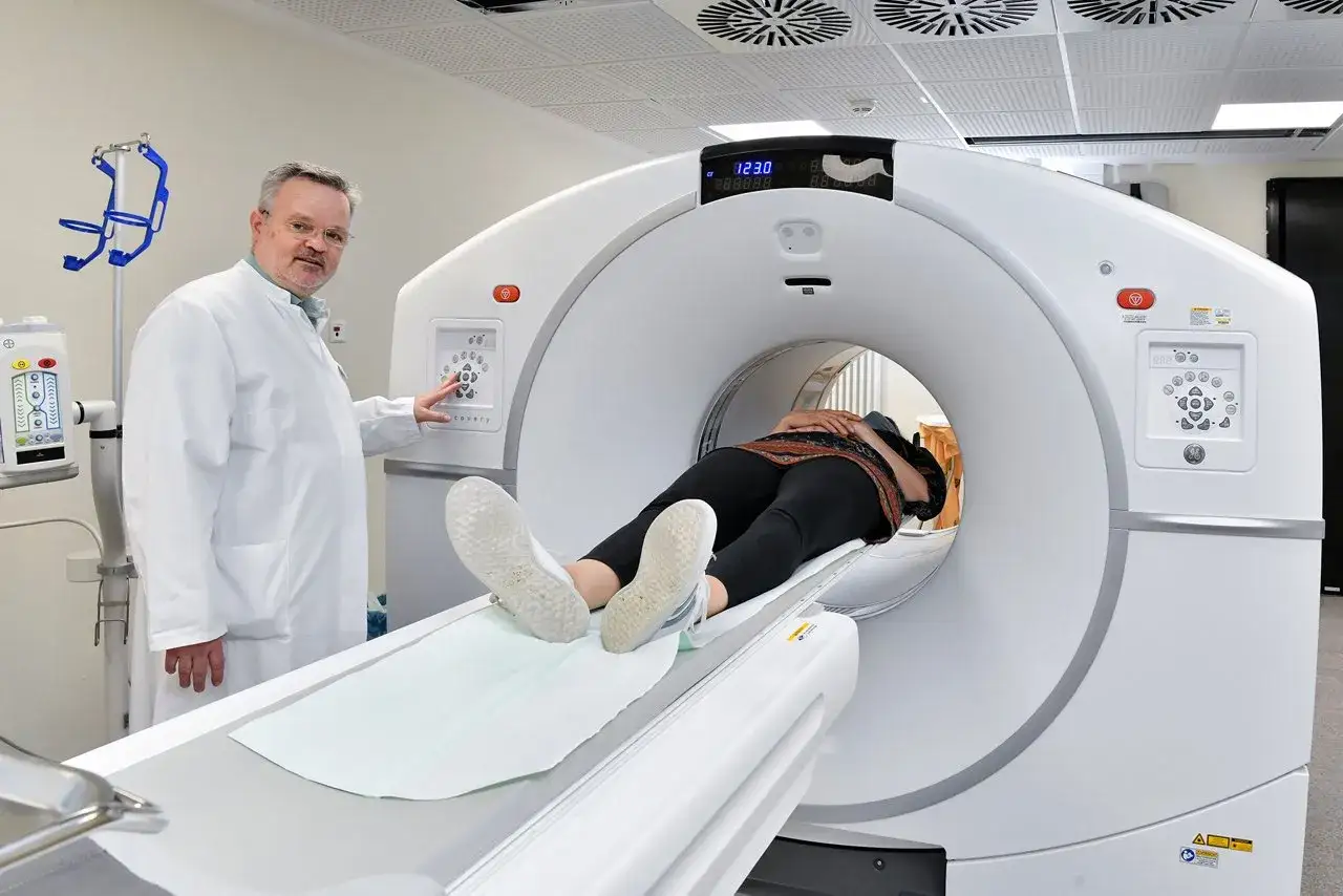 Arzt bedient PET-CT-Scanner, während Patientin für Untersuchung liegt.