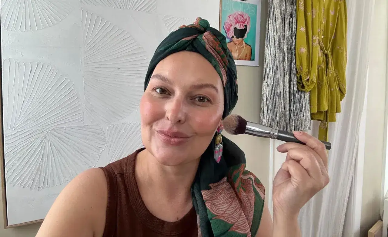 Frauen mit Kopftuch und Make-up-Pinsel, die sich für onkologische Kosmetik vorbereitet.